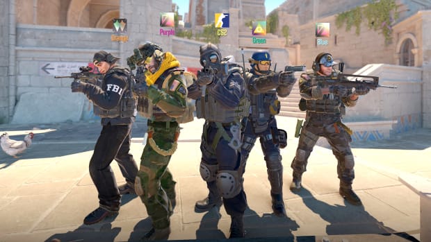 Five men wearing camo, helmets, and body armor stand in a loose V-shape in the middle of a paved plaza, pointing guns ahead of themselves